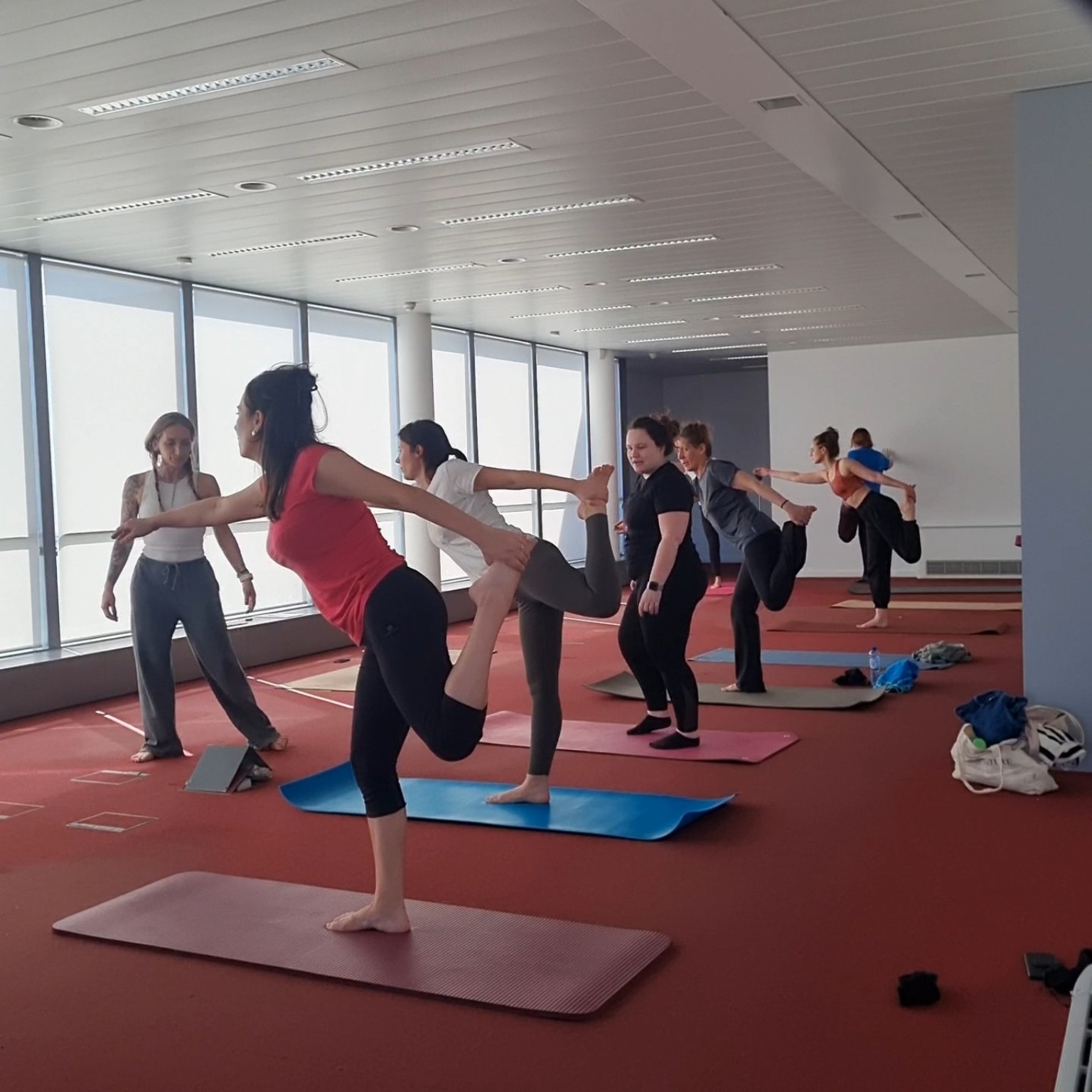 Séance de yoga en entreprise chez Notalex : un groupe de collaborateurs en posture d'équilibre sur des tapis dans une salle lumineuse