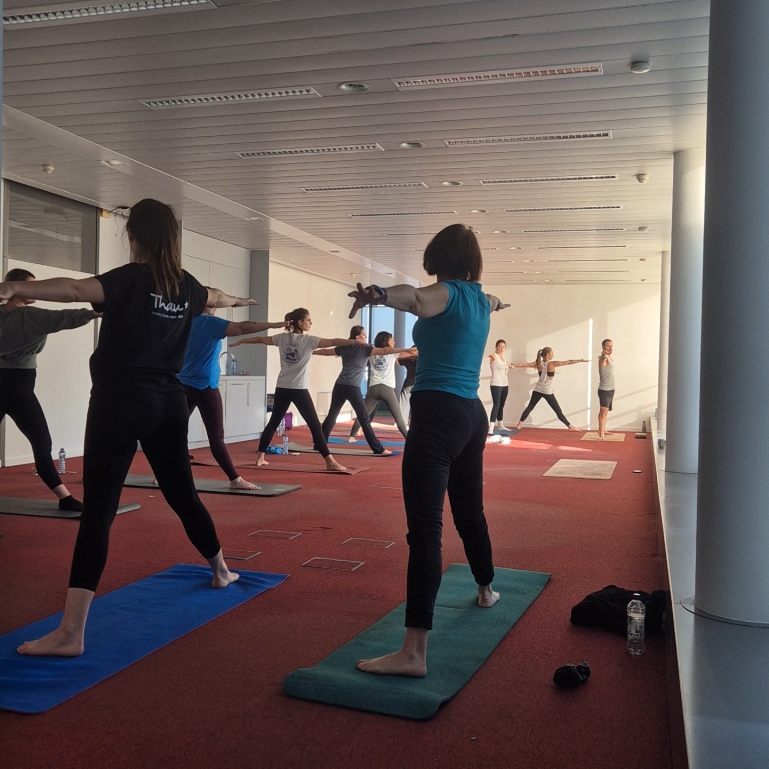 La professeure de yoga circule parmi les participants pendant une séance Reborn at Work en entreprise